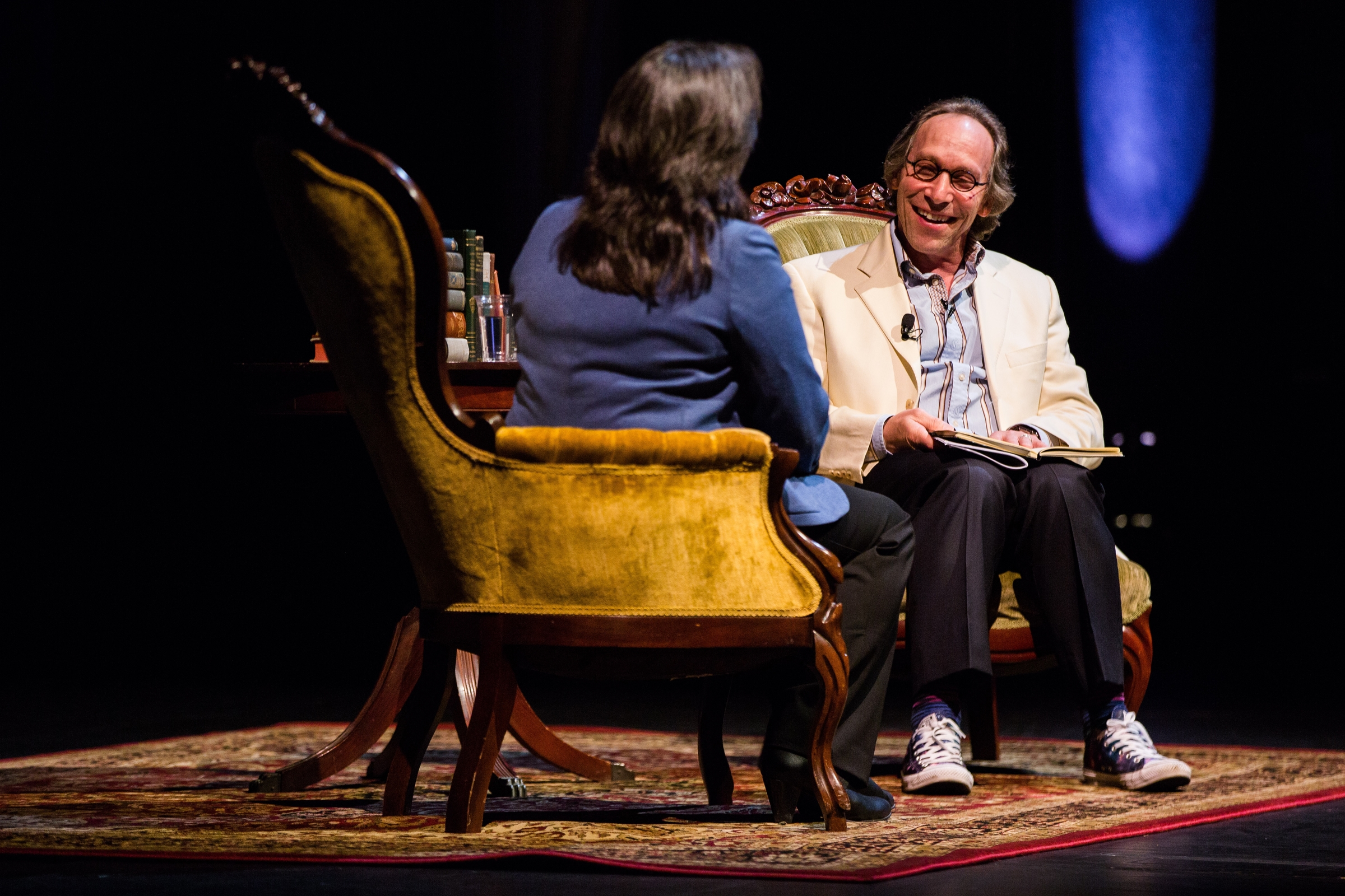 A man and a woman sit in easy chairs on a stage discussing science writing.
