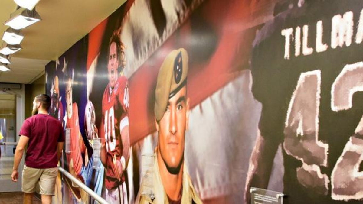 Picture of two people walking down a hallway with Pat Tillman graphics on one wall.