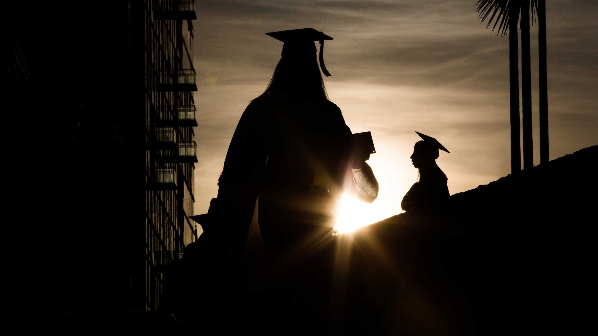 Graduates are silhouetted against the setting sun