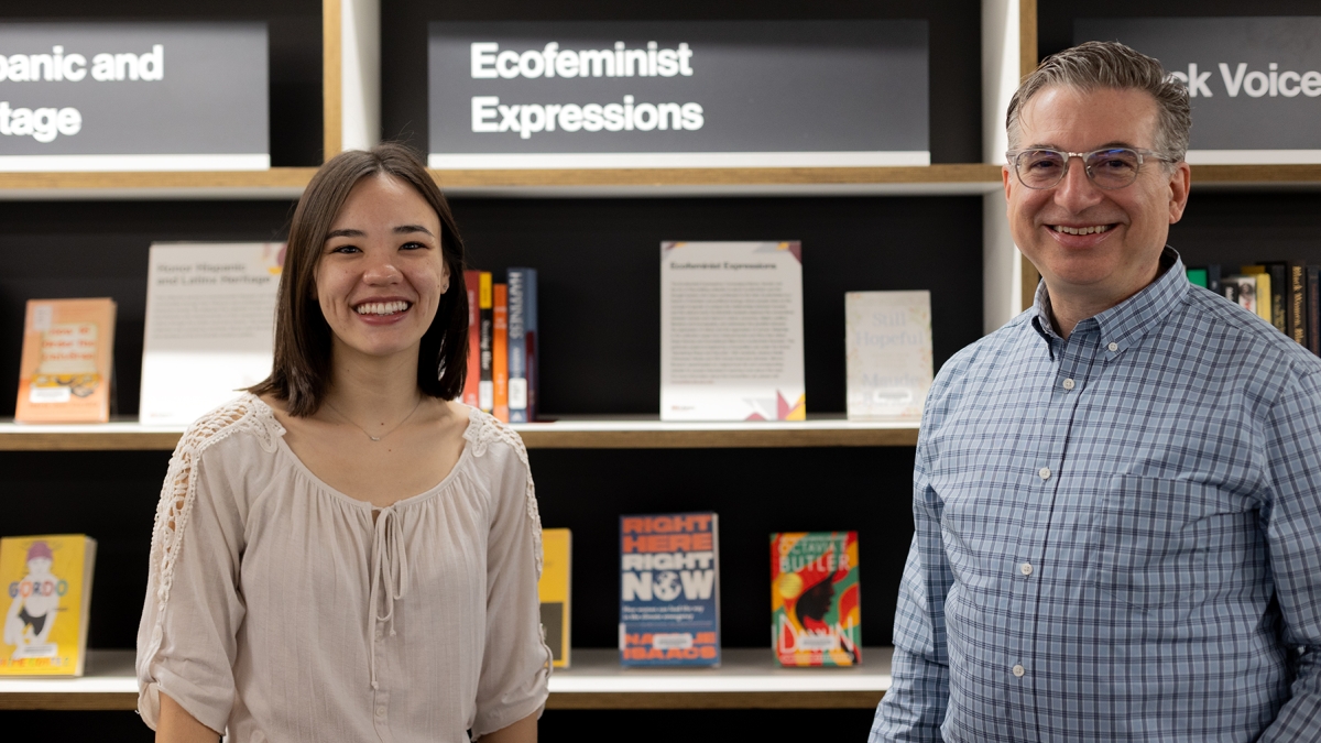 Two people standing in front of a bookshelf smiling