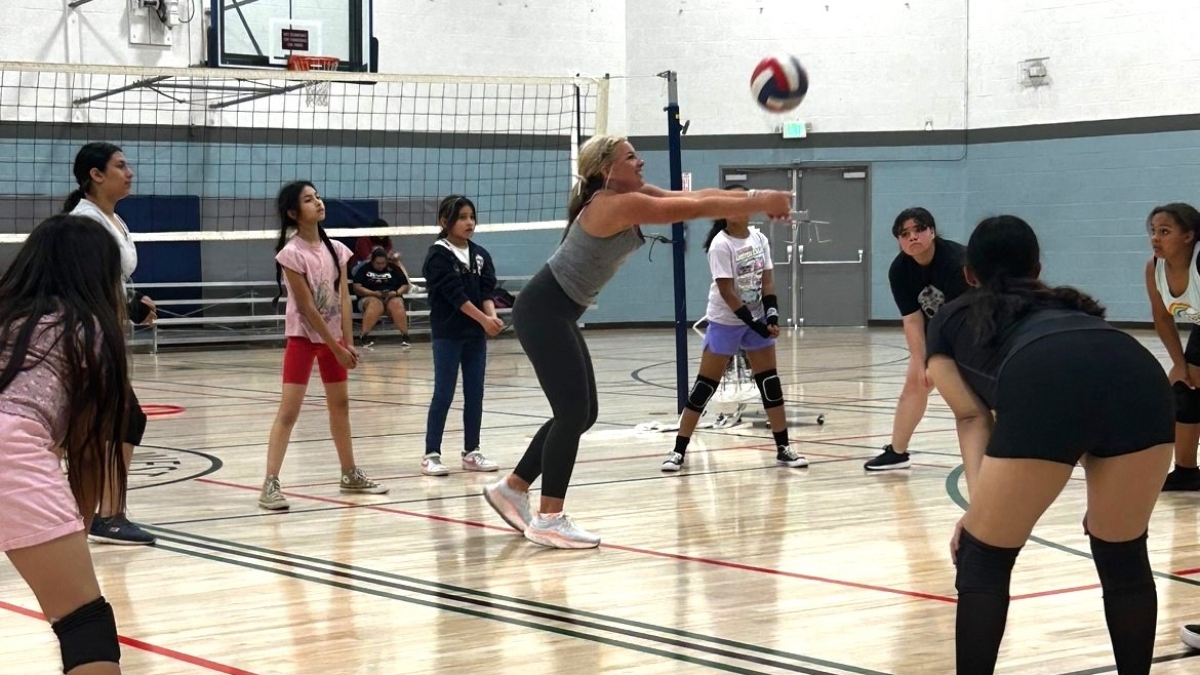 A group of girls in a gym playing volleyball