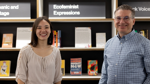 Two people standing in front of a bookshelf smiling