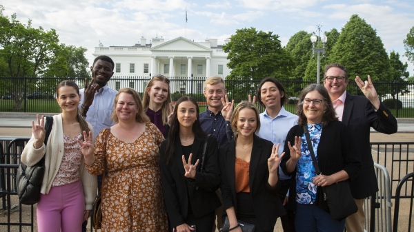 8 students and 2 professors stand in front of the White House