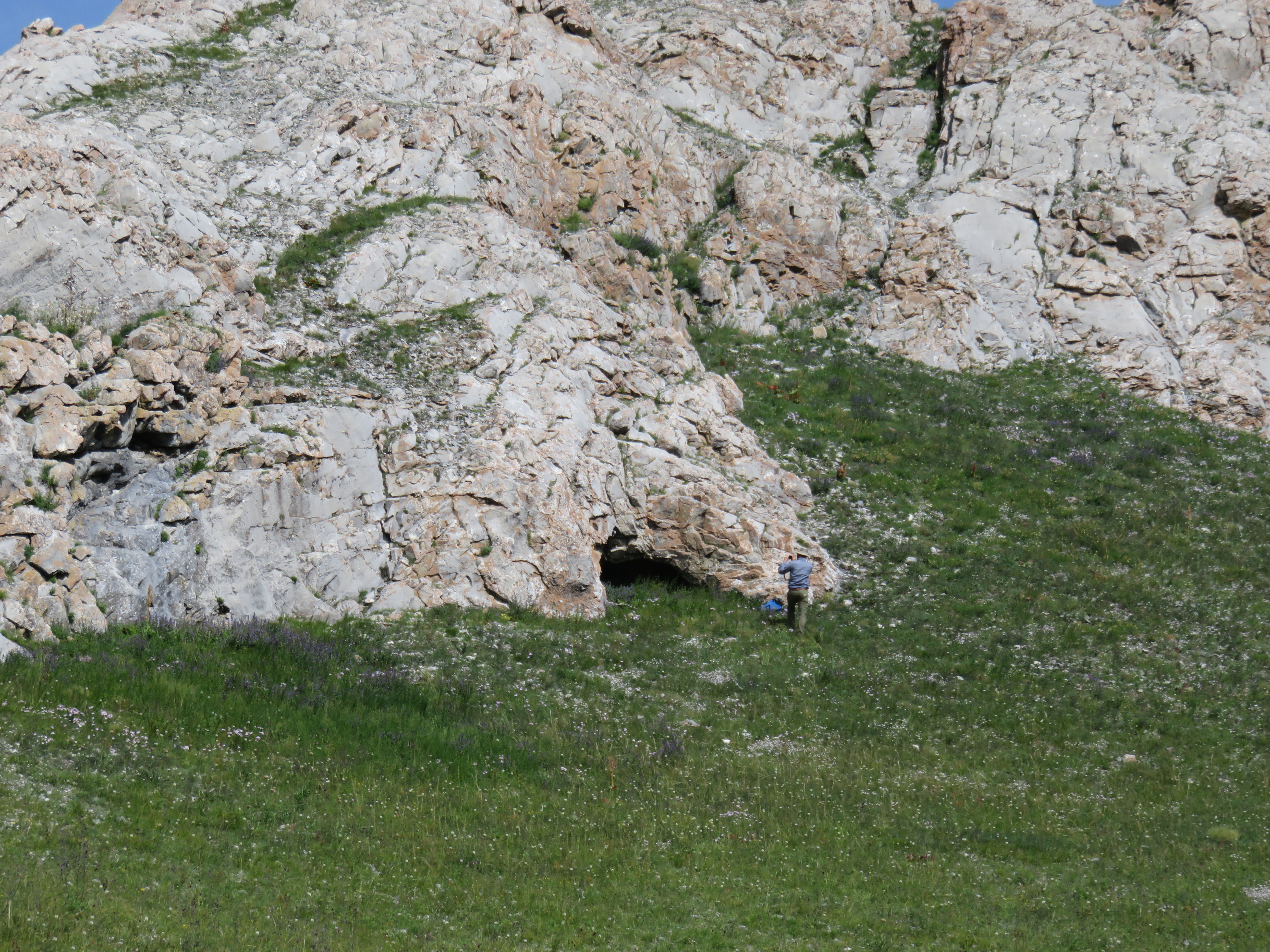 Photo of Dr. Perreault collecting data in front of a rock shelter in Mongolia
