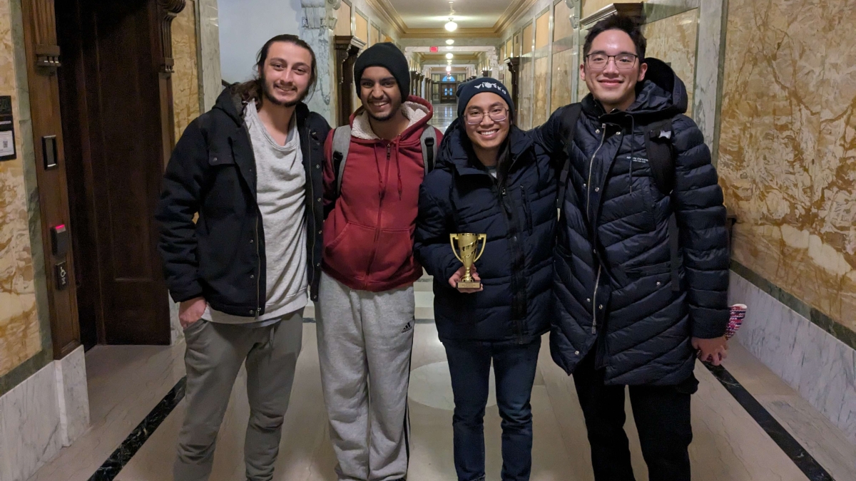 Group photo of four ASU students, with one holding a small trophy.