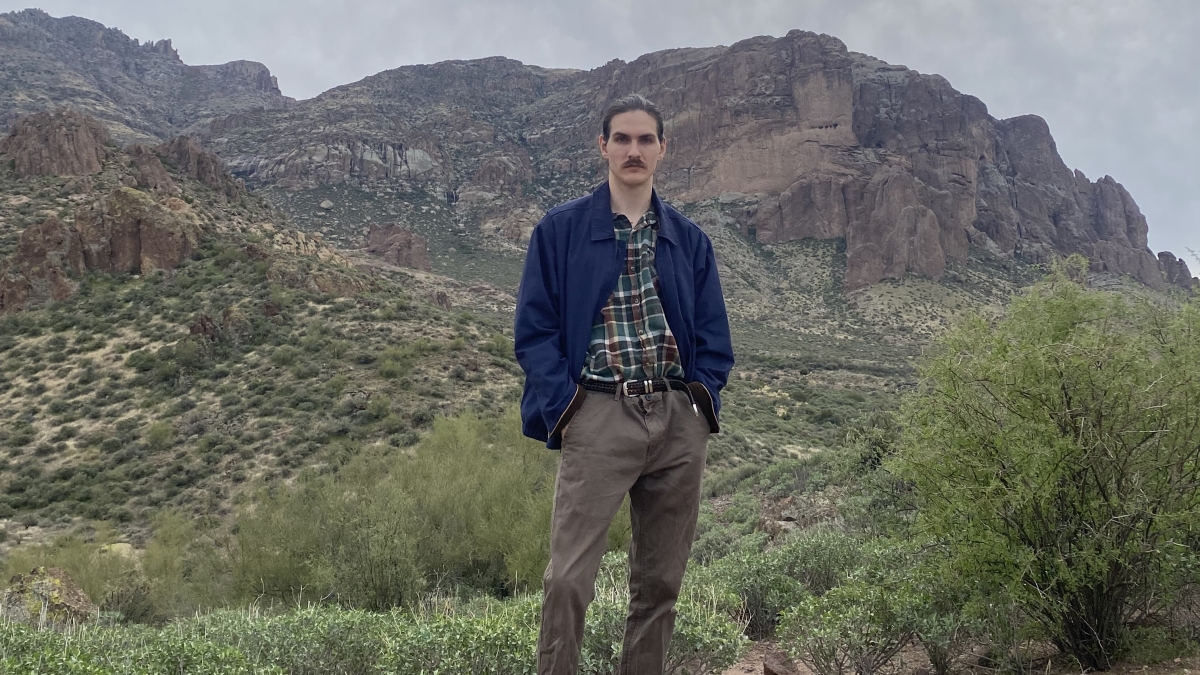 ASU grad Charles Howell stands outside in front of desert mountains