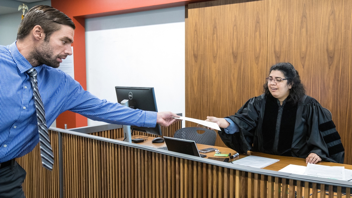 man passing woman dressed as a judge a piece of paper