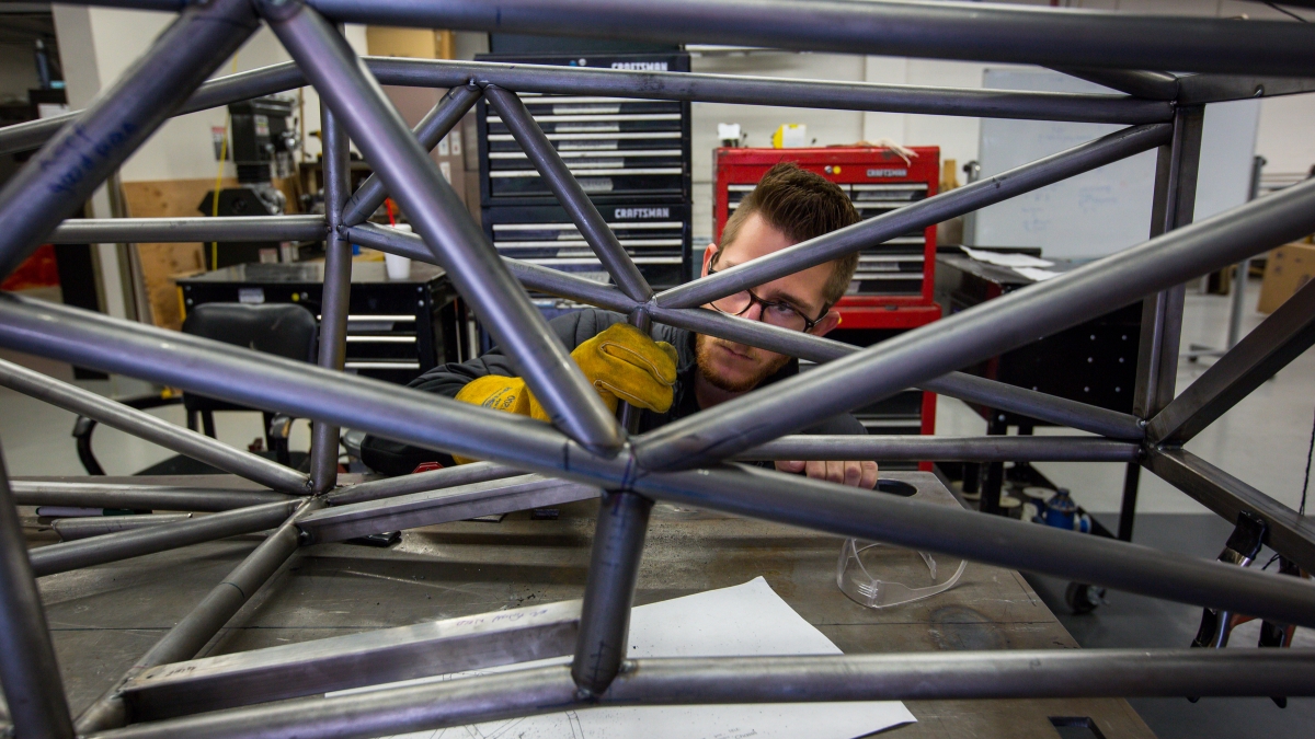 A student engineer works on the chassis of a race car.