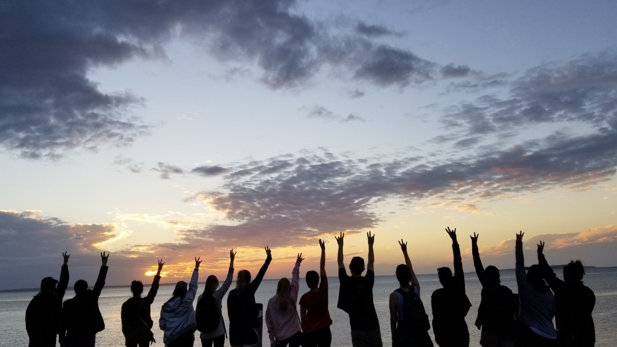 students make pitchfork sign at Australian beach sunset