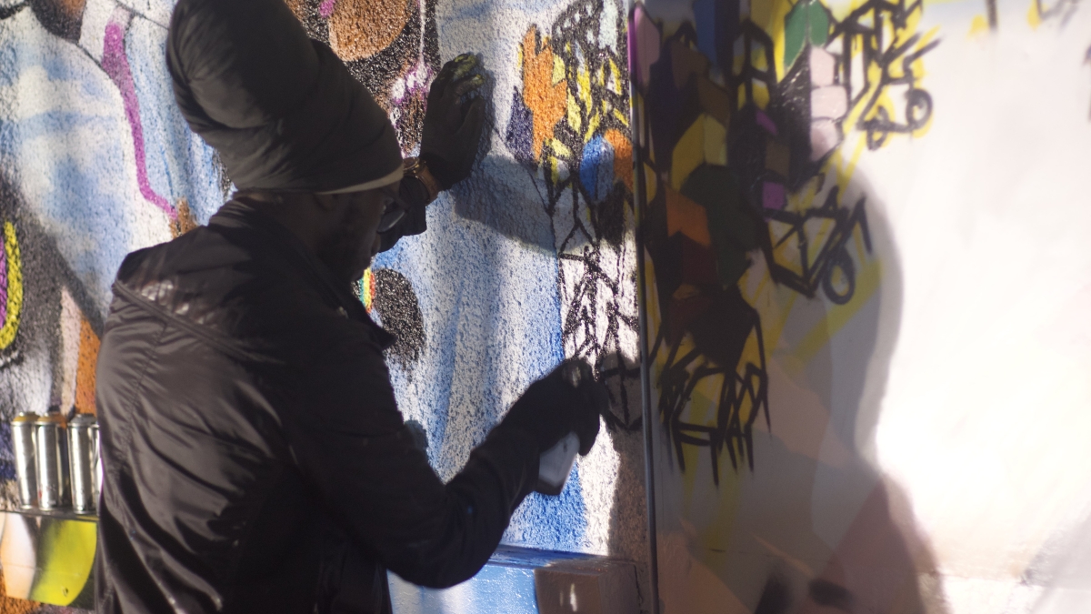 Graffiti artist works on mural