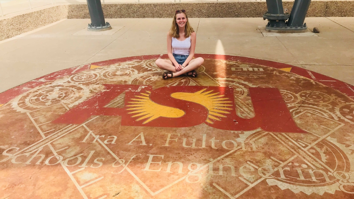 Incoming engineering first-year student Emily Hagood poses on a sidewalk with the ASU engineering school logo