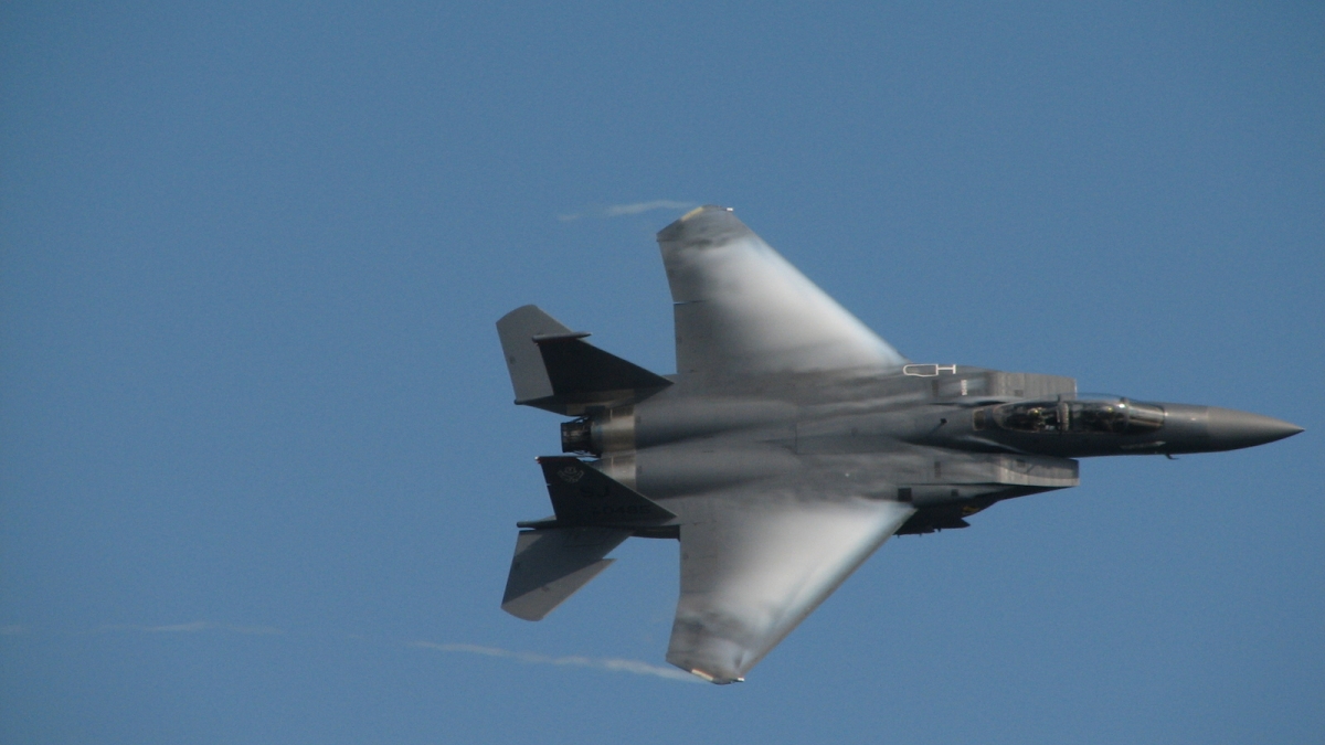 F-15 jet flies through the blue sky.