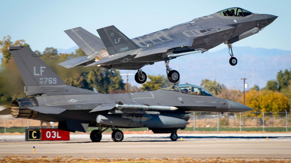 An F-35A Lightning II lands while an F-16 Fighting Falcon prepares for takeoff at Luke Air Force Base.