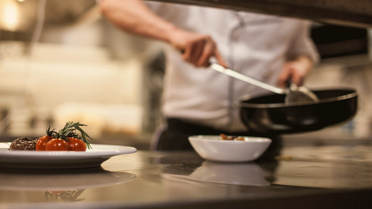 A chef stirs a pan in a restaurant kitchen