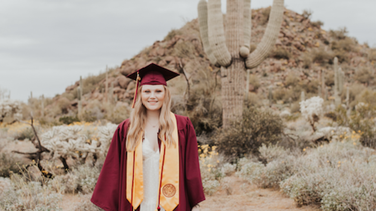 Picture of Kennedy Schneeberger in cap and gown by large cactus