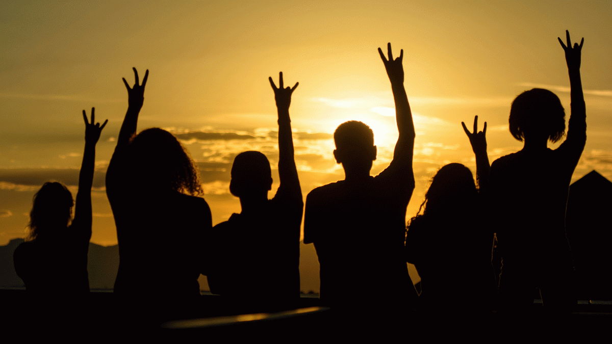 A group of students is silhouetted against a sunset