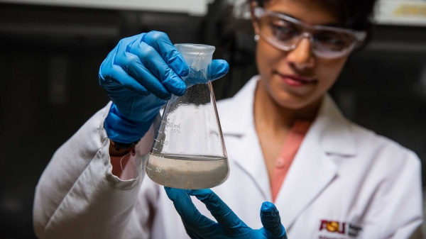 woman in lab holding beaker of liquid