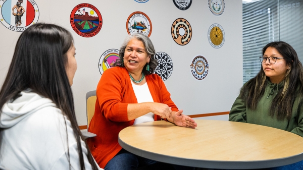 Three Native women talking at a table.