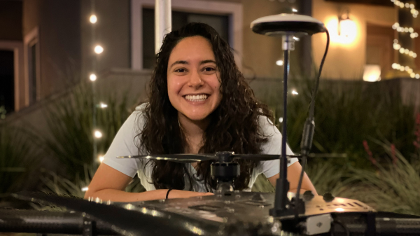 Portrait photo of Media Arts and Sciences PhD graduate, Alejandra Rodriguez Vega, drone mechanism designed for flight in the foreground, Ale in the background