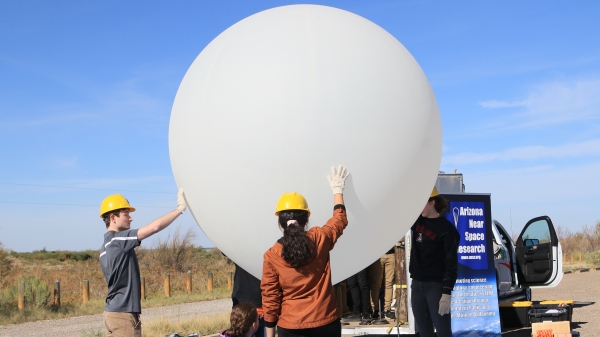 People supporting a large, white balloon.
