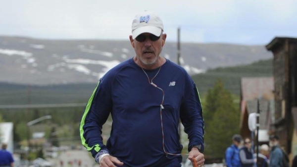 A man in athletic gear runs near a mountain.