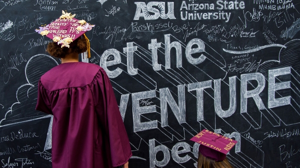 New college graduates write on a chalkboard wall