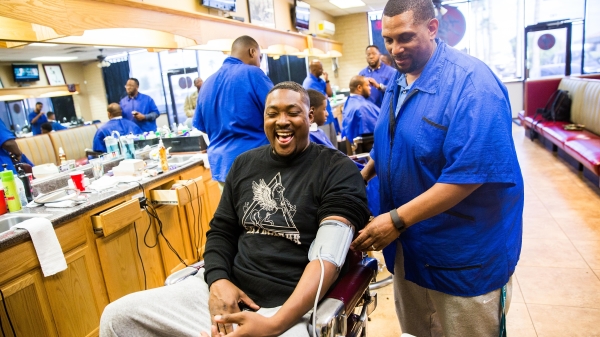 A man has his blood pressure taken at a barbershop.