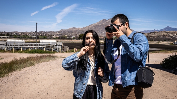 Student taking photo at water plant in Nogales while student next to him helps