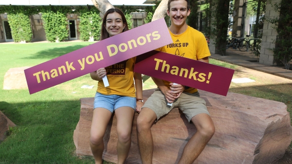 students holding signs that say "Thank you Donors" and "Thanks!"