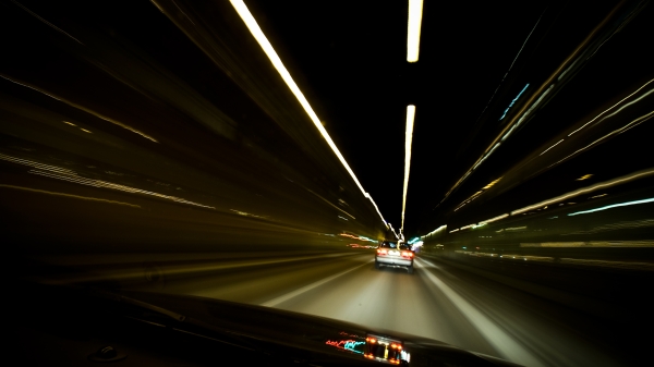 view from behind the wheel of the car at night with light trails speeding by