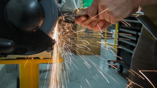 A student grinds down car parts amid a spray of sparks in the Formula SAE club's shop.