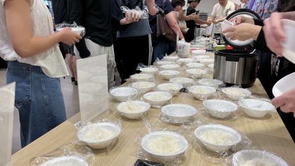 Students lining up at table to make rice balls.