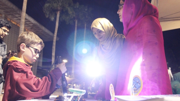 Above: Hira Rehman (in pink) and Asma Shamim (in gold) demonstrate the power of photovoltaics with members of the Tempe community during Night of the Open Door. Photographer Erika Gronek/ASU