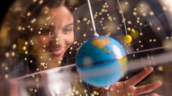 student smiling and looking at a globe