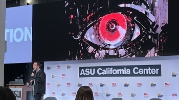 Person giving a talk on stage with an ASU California Center sign in the background.