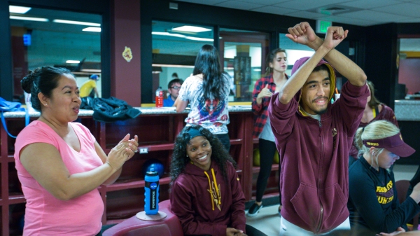 Special Olympian Jorge Marquez, 16, of Mesa, celebrates a strike at Sparky's Den in the Memorial Union basement on Tuesday, Nov. 10, 2015. Behind him, his mother, Dominique Colunga (left) and basketball player Elisha Davis (center) join in the merriment.