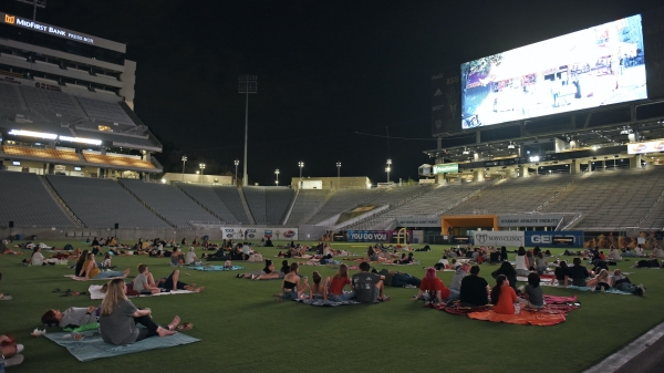 Frank Kush Field at night is scattered with families on blankets watching the video screen