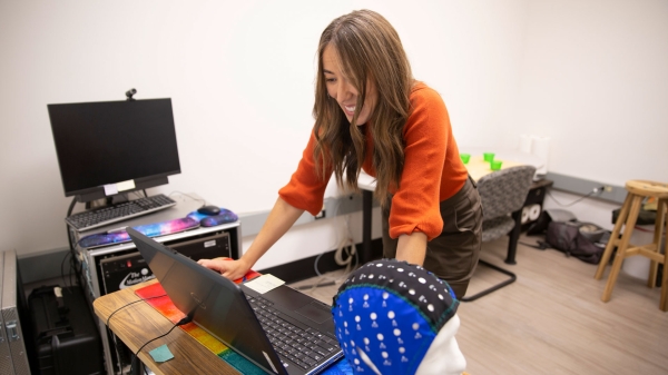 Sydney Schaefer looks at a laptop on a desk while smiling.