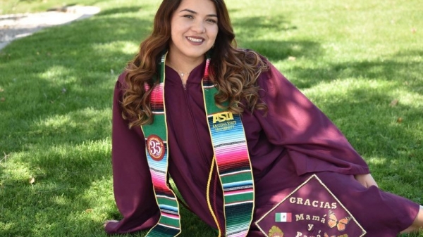 Picture of Maricela Diaz in cap and gown sitting on green grass in the shade