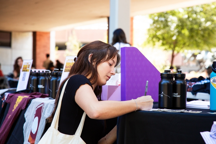 Woman writing on paper at tabling event