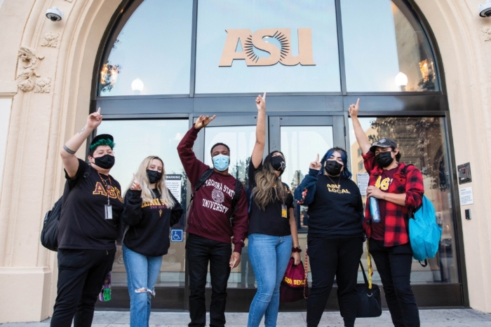 Students raise hands in excitement in front of ASU building in California