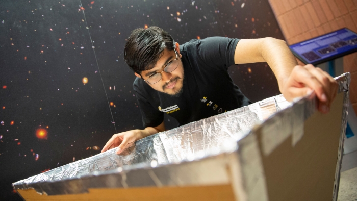 Ritwik Sharma works with a foil-covered square structure.