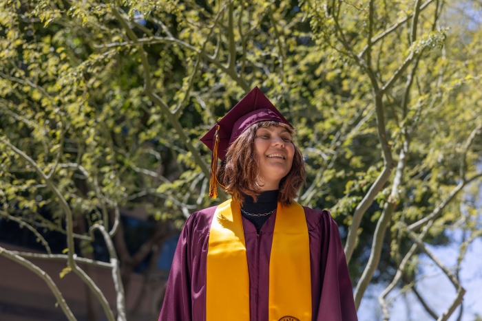 Portrait of Mollie McCurdy in an outdoor setting wearing ASU graduation robe, cap and stole