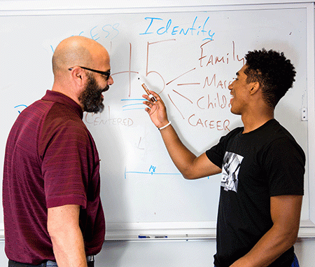 Alonzo Jones and a student write on a whiteboard
