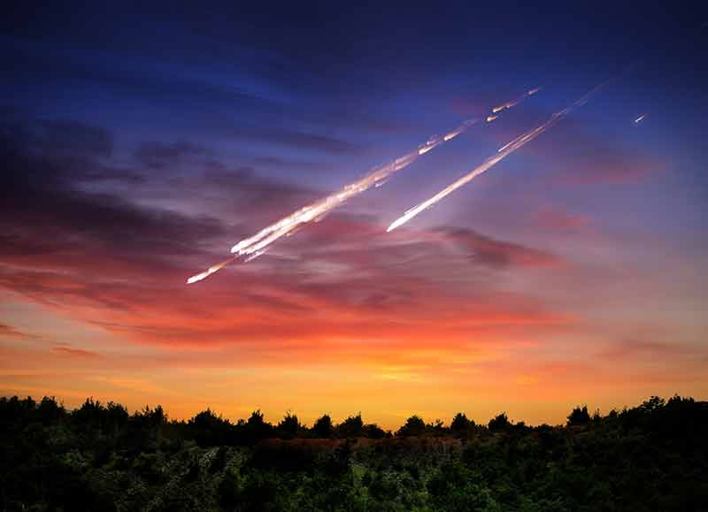 meteorite falling to Earth over treeline