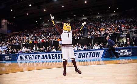 ASU mascot Sparky stands on a basketball court and waves to the crowd