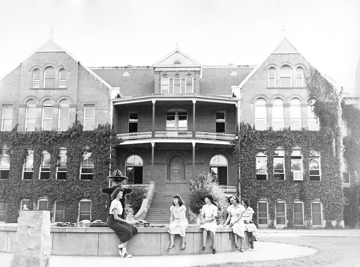 Five women sitting on the fountain in front of Old Main, Arizona State University (ASU), Tempe, Arizona (circa 1940)